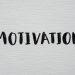 Inspirational word 'Motivation' in black on a white textured canvas background.
